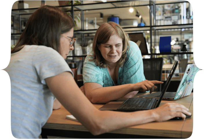 A fellow student helping a peer with their computer setup. Pointing at something specific on the screen.