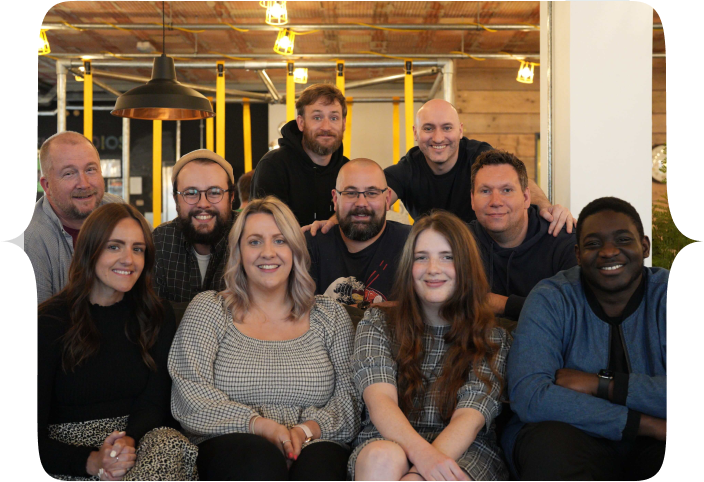 The Tech Educators team, all seated and standing around a couch in FUEL studios, Norwich
