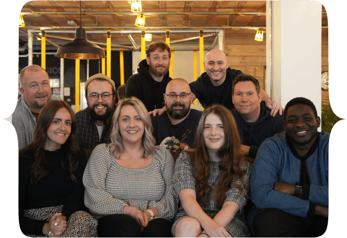 The Tech Educators team, all seated and standing around a couch in FUEL studios, Norwich