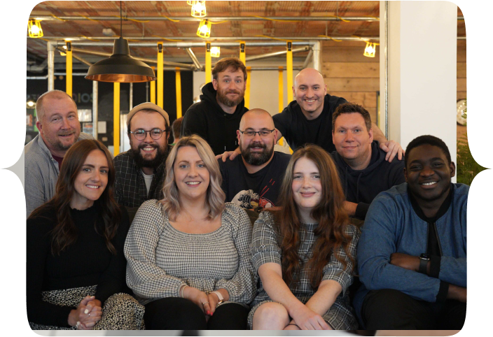 The Tech Educators team, all seated and standing around a couch in FUEL studios, Norwich
