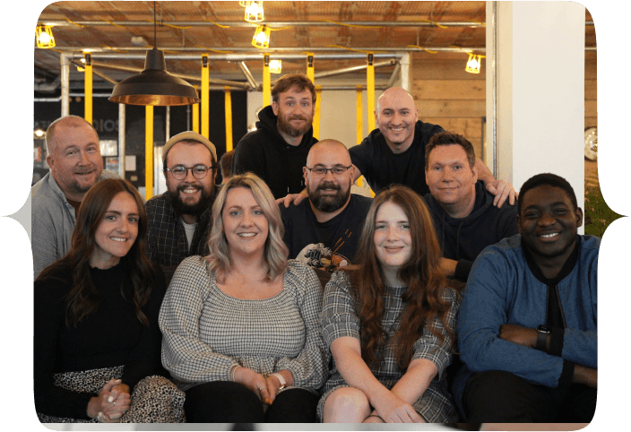 The Tech Educators team, all seated and standing around a couch in FUEL studios, Norwich